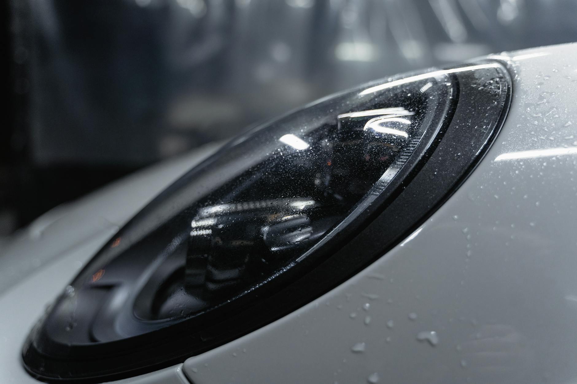 Reflektor nowoczesnego auta pokryty kroplami wody